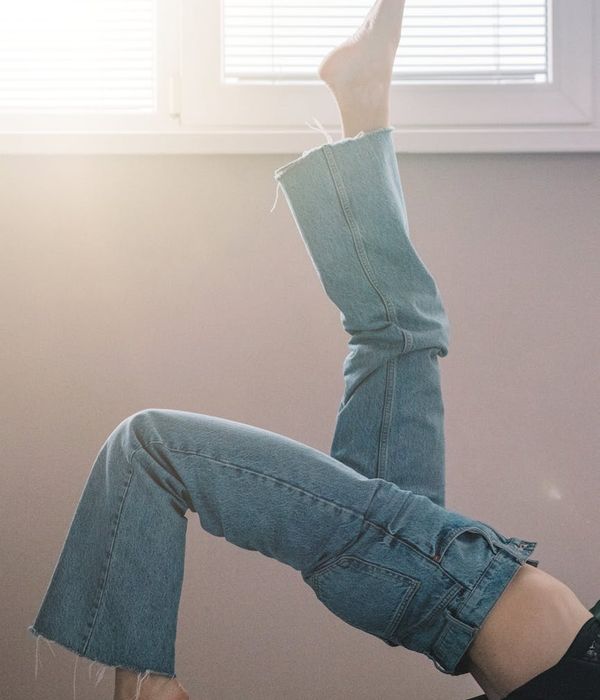 Person in a calm and focused state, stretching gently by a window with soft light.